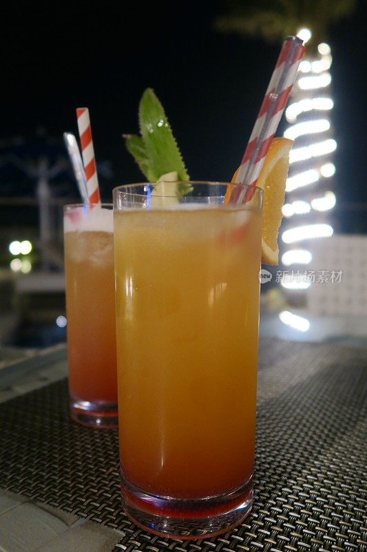 “海滩上的安全性行为”无酒精鸡尾酒/鸡尾酒饮料在高球杯与菠萝和橙色装饰，户外印度酒吧背景照片